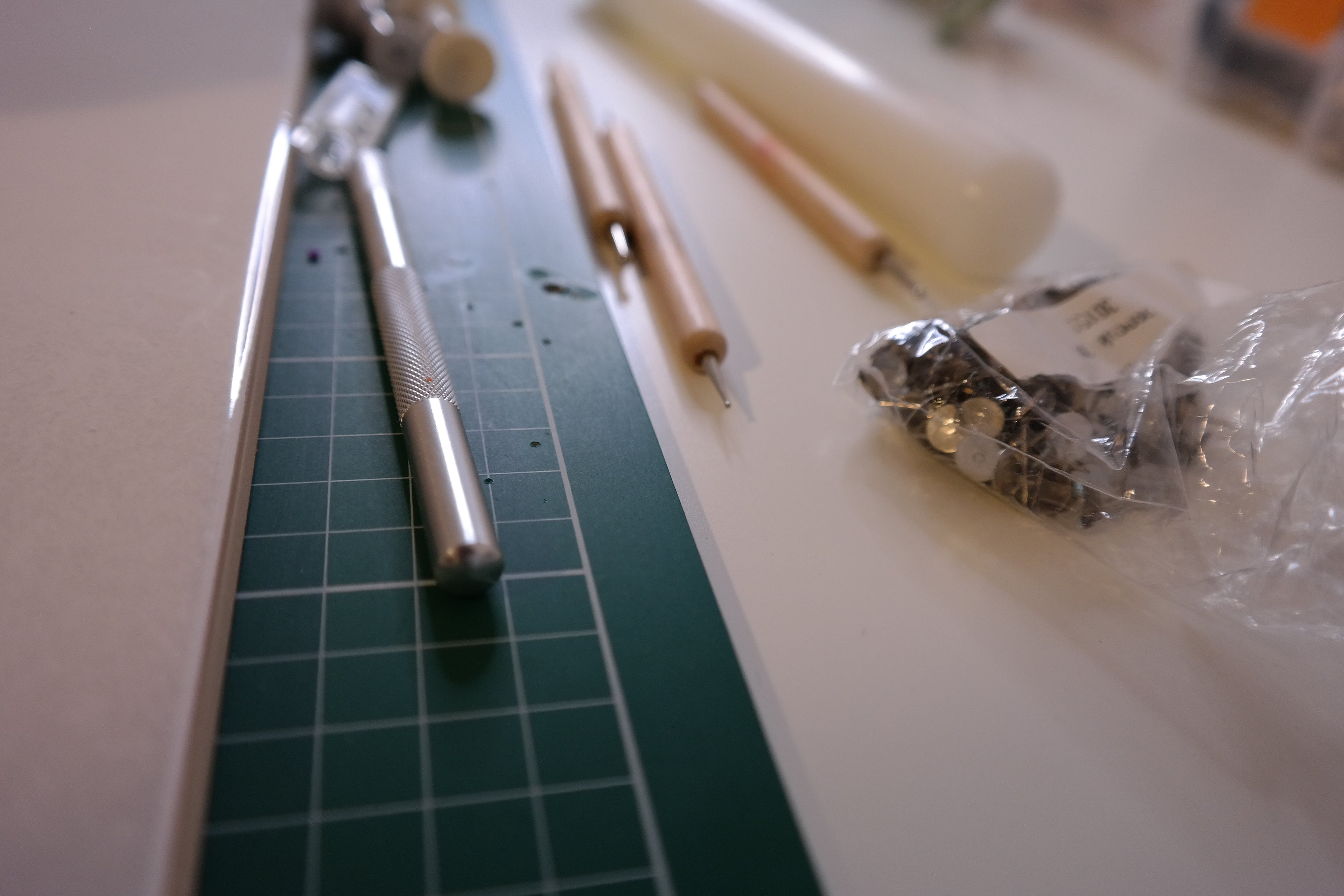 Polymer clay tools and materials on a cutting mat with a blurred background